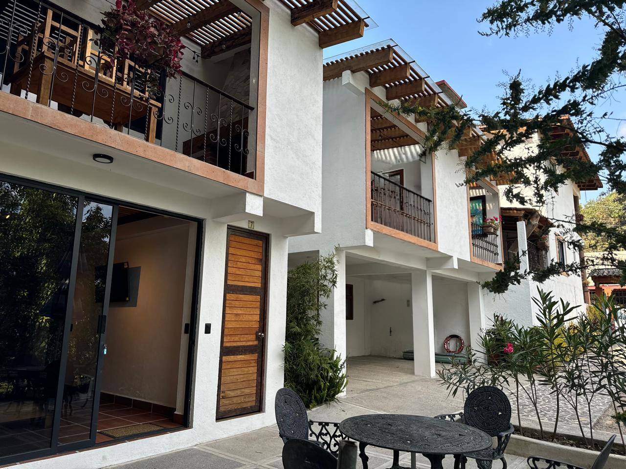 Fachada de Beto's Hospedajes con balcones de herrería, pérgolas de madera, terraza con mesa de hierro forjado y jardín en Avándaro